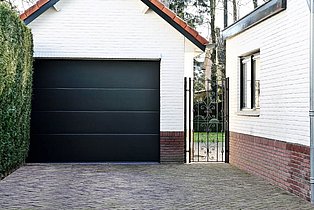 Weiße Garage mit schwarzem Garagentor