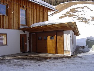 Haus im Schnee, mit hellbraunem Garagentor